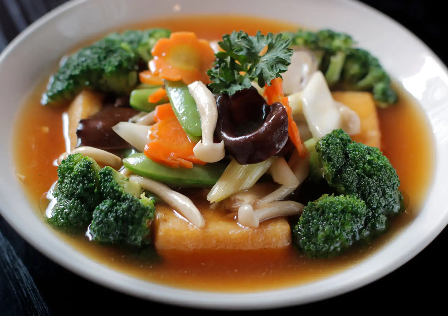 Stir‑fried vegetables and tofu in savory brown sauce with broccoli, mushrooms, and carrots on plate.