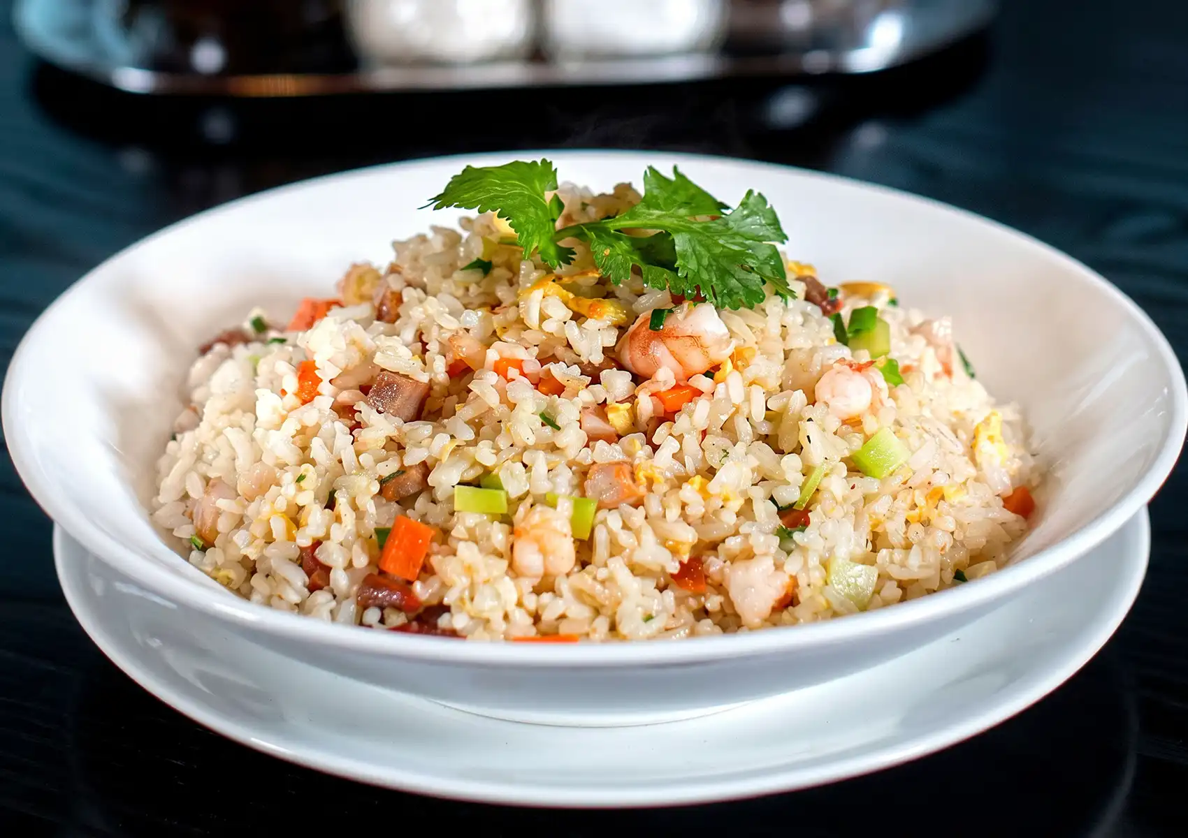 Colorful fried rice with shrimp, egg, and vegetables served in white bowl, garnished with fresh cilantro.