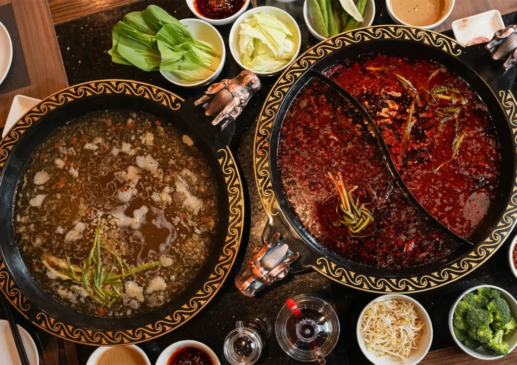 Best hotpot broths in Sanur with dual pots of clear herbal and spicy chili broth, surrounded by fresh vegetables and condiments for communal dining.