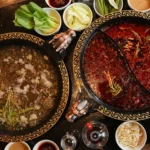Best hotpot broths in Sanur with dual pots of clear herbal and spicy chili broth, surrounded by fresh vegetables and condiments for communal dining.
