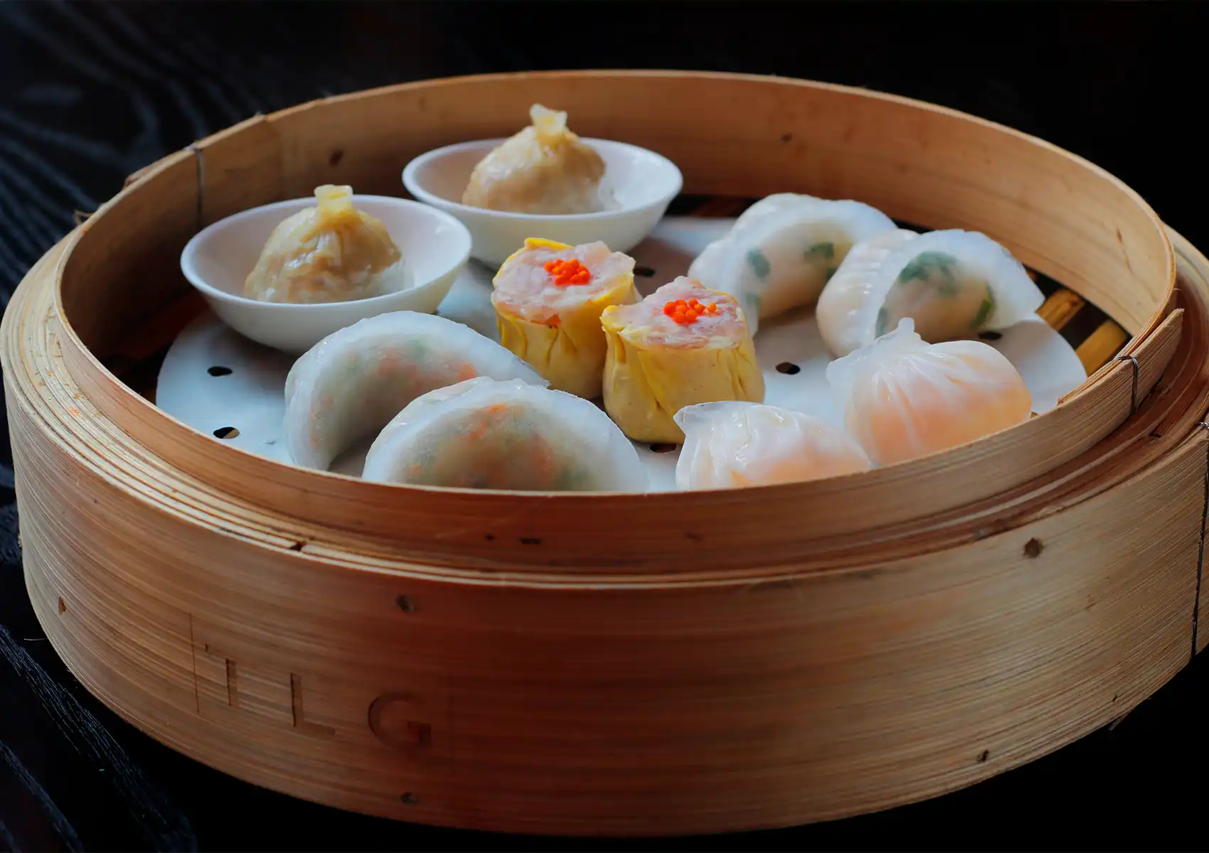 Dim sum basket with har gow, siu mai, and assorted steamed dumplings served in bamboo steamer in Bali.