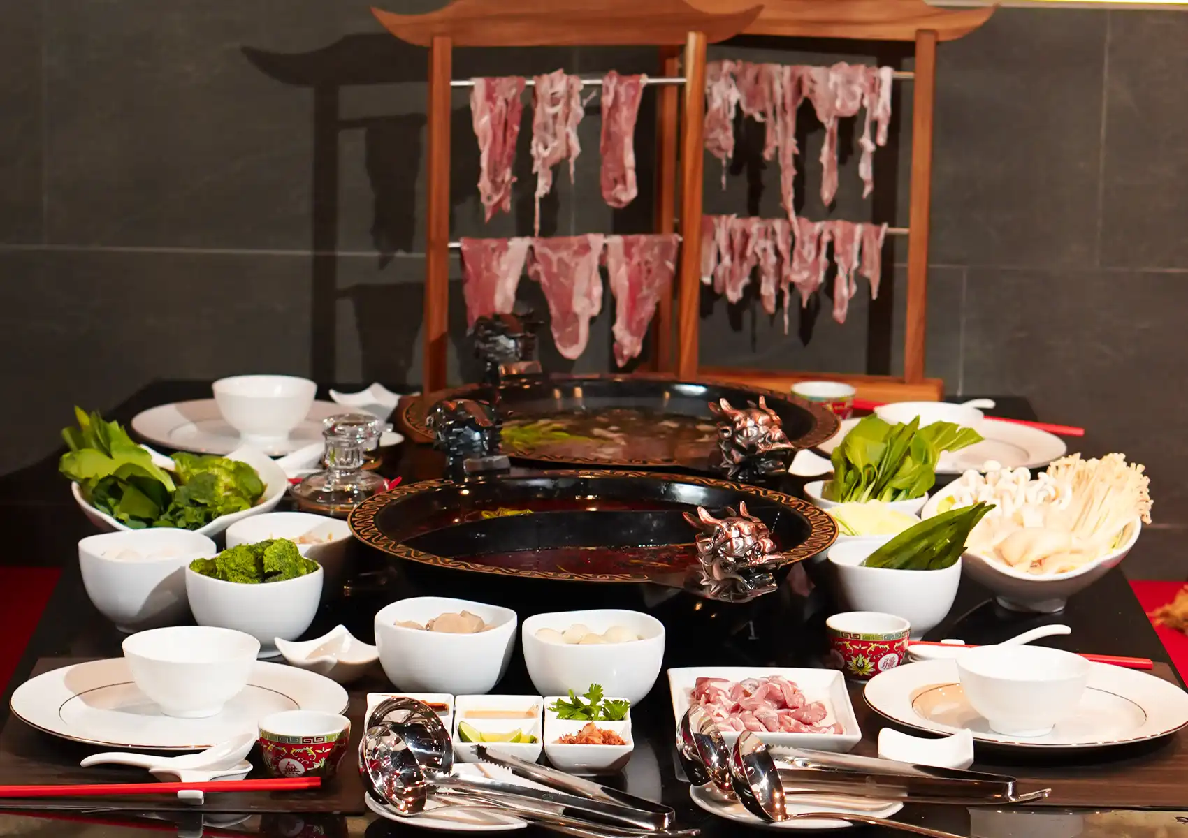 Chinese hot pot in Bali with ornate dragon‑handled vessels, fresh vegetables, sliced meat, and dipping sauces for communal dining.