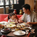 Kid‑friendly Chinese food in Bali with rice, steamed buns, and vegetables shared at a cozy restaurant table.