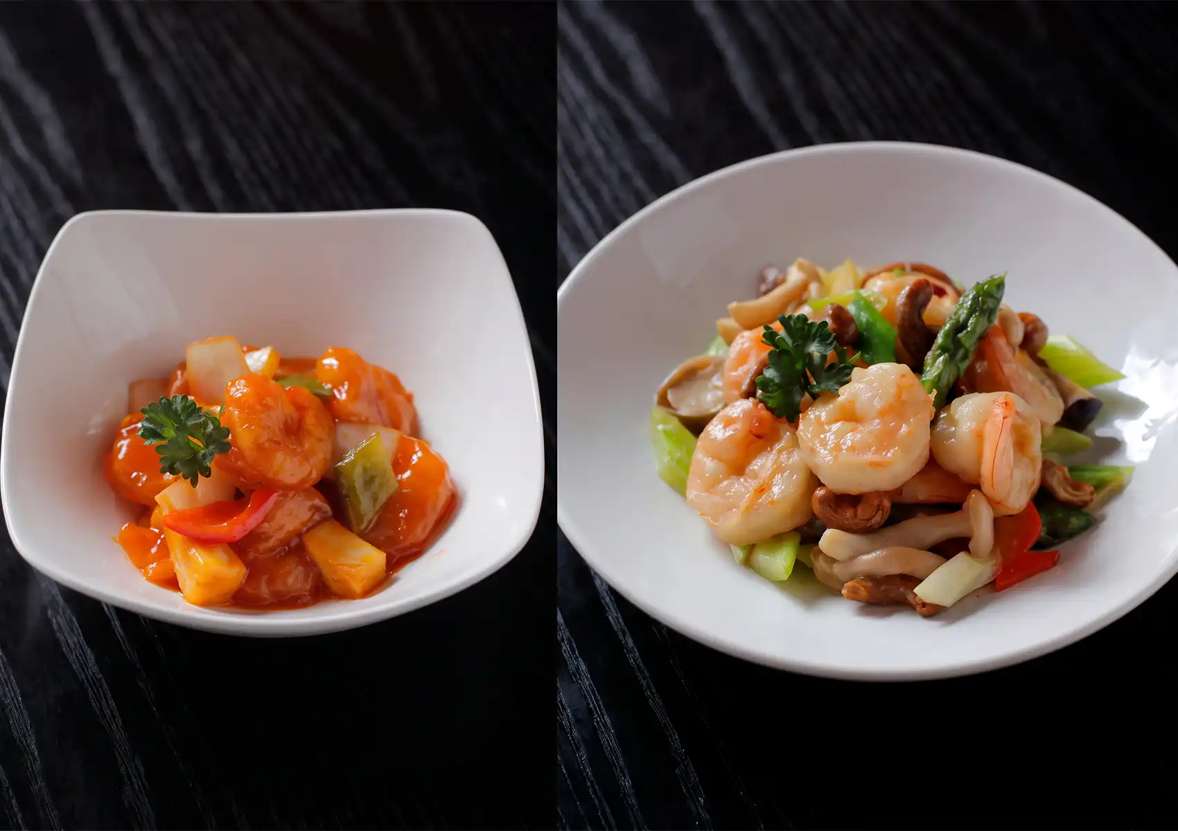 A side-by-side presentation of two appetizing seafood dishes in white bowls on a dark wooden table, featuring vibrant sweet and sour prawns on the left and a delicate prawn stir-fry with asparagus and cashews on the right, served at a Cantonese restaurant in Bali.